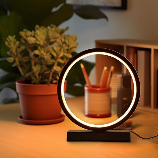 Lampe LED circulaire minimaliste allumée sur une table de chevet avec des fleurs et des crayons